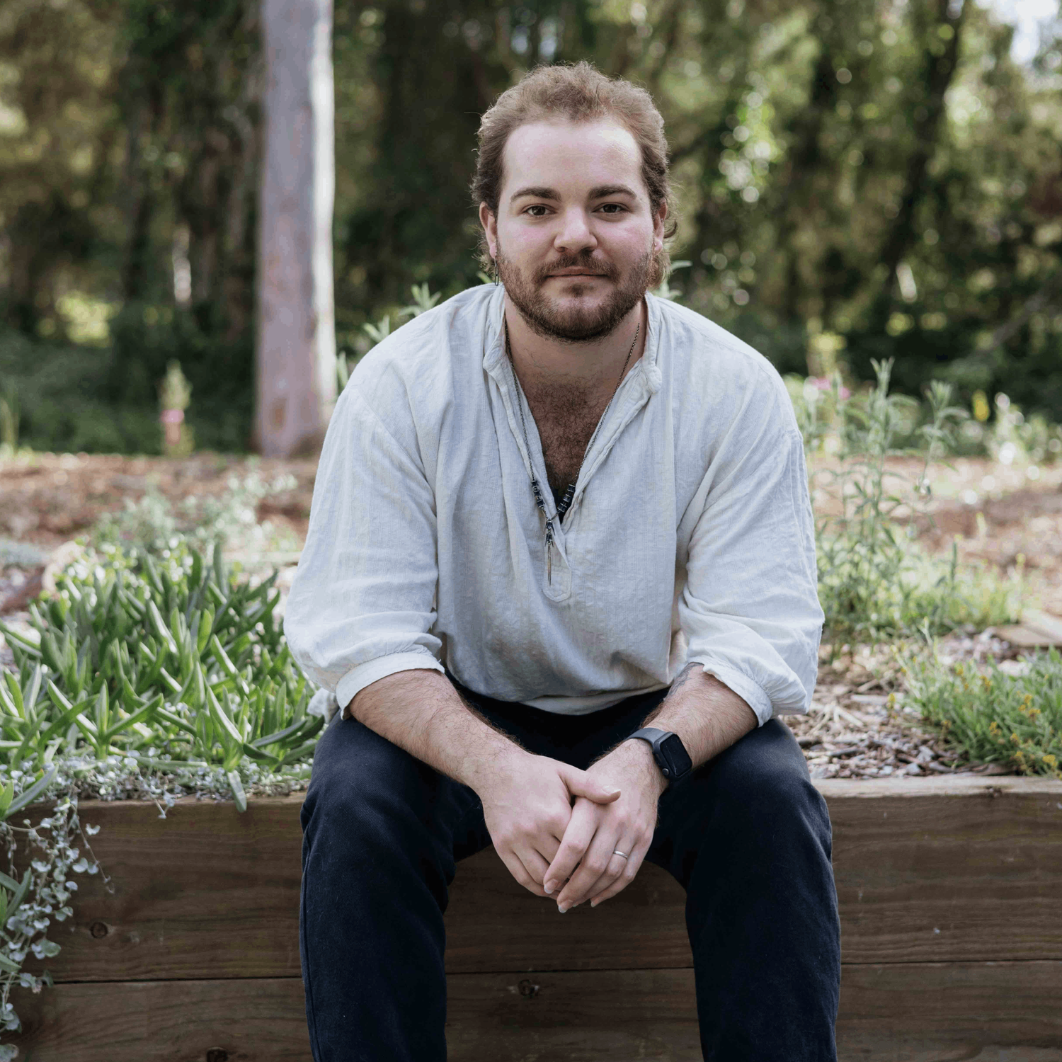 Eric sitting on edge of a wooden garden bed